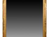 un miroir à cadre doré accroché à un mur blanc, sur fond noir