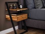 une table en bois sur laquelle se trouve une horloge, à côté d'un lit