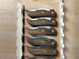five knives in a display case on a wooden table