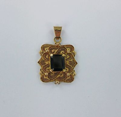 un pendentif en or orné d'une pierre noire au centre