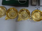 four gold dishes and a lighter on a table