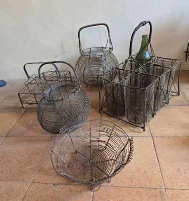 trois paniers contenant des bouteilles de vin, posés sur un sol carrelé