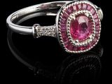 une bague sertie d'un saphir rose et de diamants, posée sur un fond noir