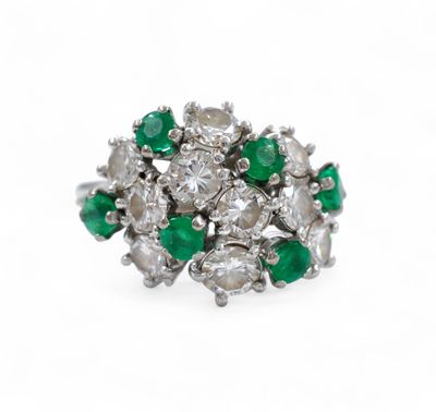 a close up of a diamond and emerald ring on a white background