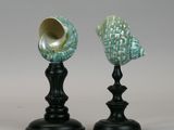 two black candlesticks with sea shells sitting on top of them