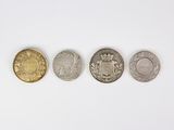 four different coins are arranged in a row on a white surface