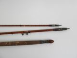 two old fishing rods on a white surface with a white background