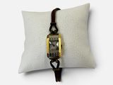 une photo d'une montre-bracelet posée sur un oreiller, sur une surface blanche