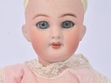 a small doll with a pink dress and a yellow headband
