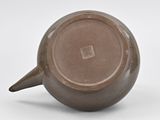 a brown cup with a handle sitting on a white surface