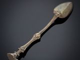 an antique silver spoon on a black surface with a black background