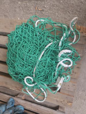 un tas de corde verte posé sur une palette, à côté d'une paire de chaussures bleues