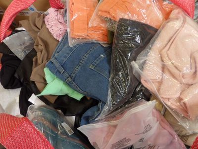 un tas de vêtements dans un sac posé sur un lit