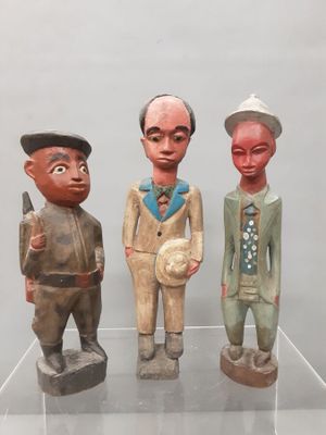 three wooden figurines of men standing on a clear shelf
