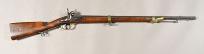un vieux fusil accroché au mur, à côté d'un mur blanc