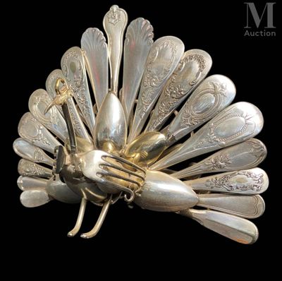 a silver peacock brooch made of spoons on a black background