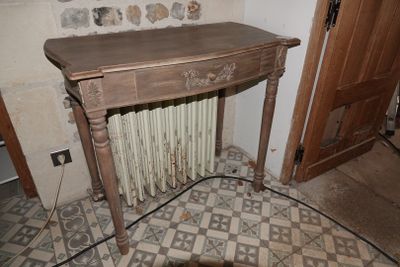 a wooden table with a radiator in the corner of a room