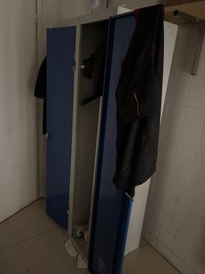 un casier bleu sur lequel est accroché un manteau, dans une pièce