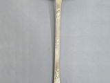 an antique silver spoon with a spoon handle on a gray background