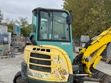a yellow and green excavator that is sitting in the dirt