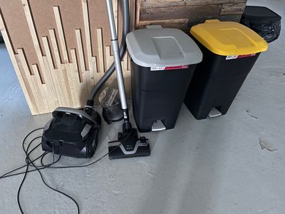 two trash cans and a vacuum on the floor