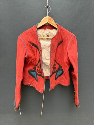 une vieille veste rouge suspendue à un cintre accroché au mur