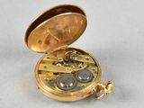 a gold pocket watch sitting on a white surface