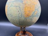un vieux globe posé sur un socle en bois, lui-même posé sur une table