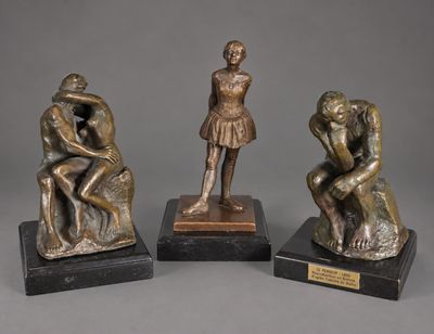 trois figurines en bronze représentant un homme et une femme assis sur un rocher