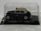 a black model car in a glass case on a white surface