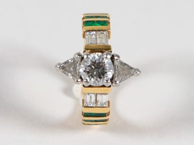gros plan d'une bague en diamant et émeraude sur une surface blanche