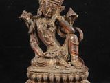une statue en bronze représentant un Bouddha assis sur un socle