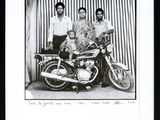 a black and white photo of a man and two women and a motorcycle