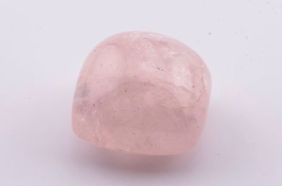 un gros plan d'un caillou rose sur une surface blanche