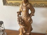 une statue représentant une femme tenant un panier de fleurs posé sur une table