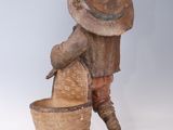 statue of a boy with a hat and a basket on a white surface