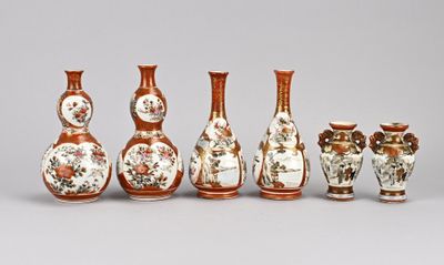 Plusieurs vases aux motifs variés sont alignés sur une surface grise