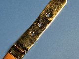 an image of a gold plated knife on a blue surface