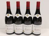 quatre bouteilles de vin rouge sont alignées sur une table