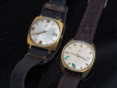 two watches sitting next to each other on a black surface