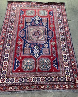 a red, blue and white rug sitting on top of a cement floor