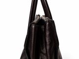the large black leather bag is sitting on a white surface