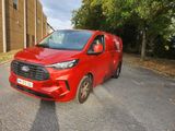 La camionnette rouge est garée sur le bord de la route, devant un immeuble.