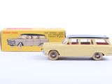 une petite voiture jaune avec une planche de surf posée dessus, devant une boîte