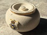 un petit pot muni d'un couvercle, posé par terre