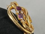 a close up of a gold ring with purple stones on a black surface