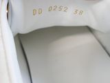 a person holding a white purse with a gold logo on it