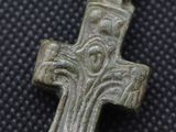 a close up of a silver cross on a black surface