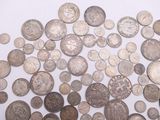 a pile of old silver coins on a white surface