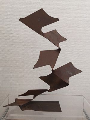 a metal sculpture of a piece of paper flying in the air